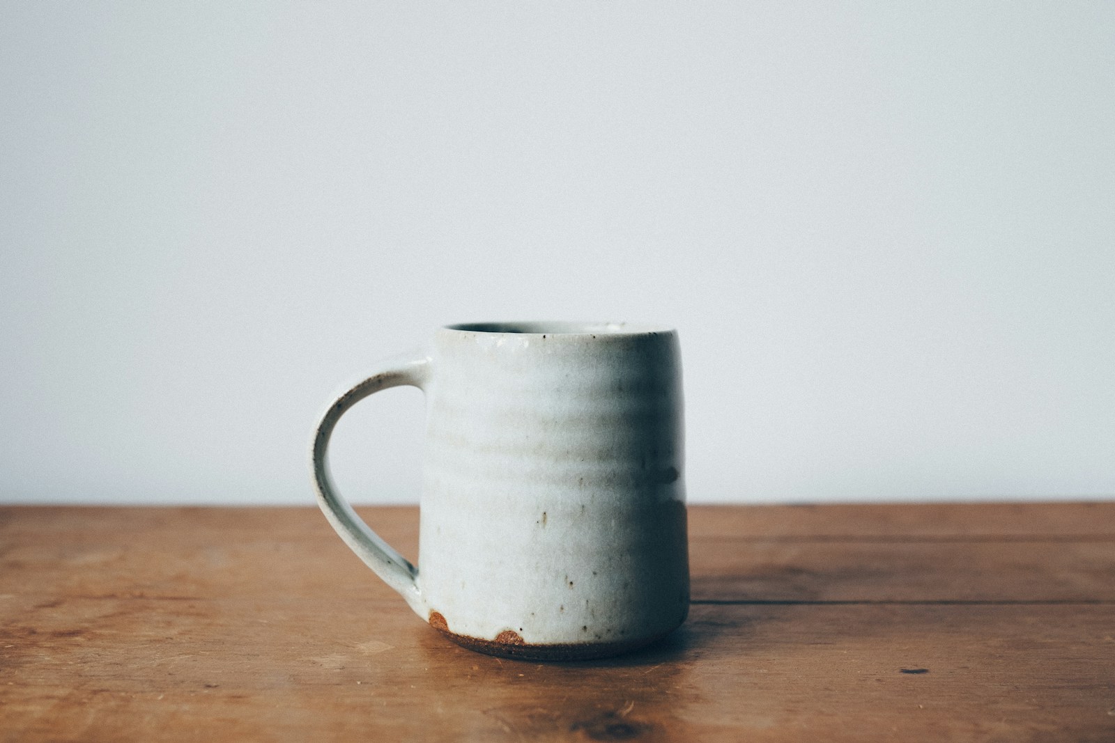 Handmade white ceramic mug on a wooden table